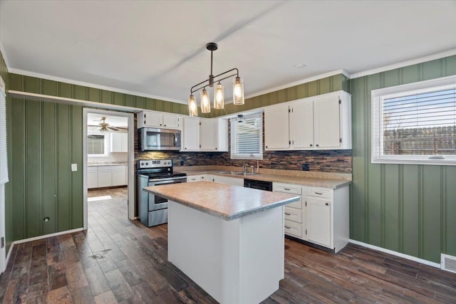 kitchen featuring stainless steel appliances, white cabinets, light countertops, a center island, and decorative light fixtures