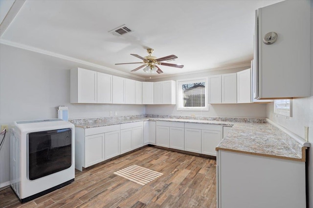 kitchen with washer / dryer, visible vents, wood finished floors, light countertops, and white cabinetry