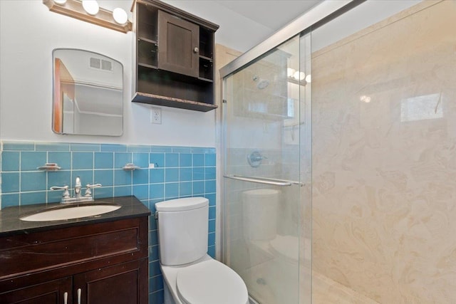 full bathroom with visible vents, toilet, vanity, a shower stall, and tile walls