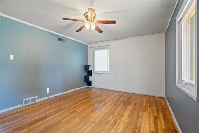 empty room with ceiling fan, ornamental molding, wood finished floors, and visible vents