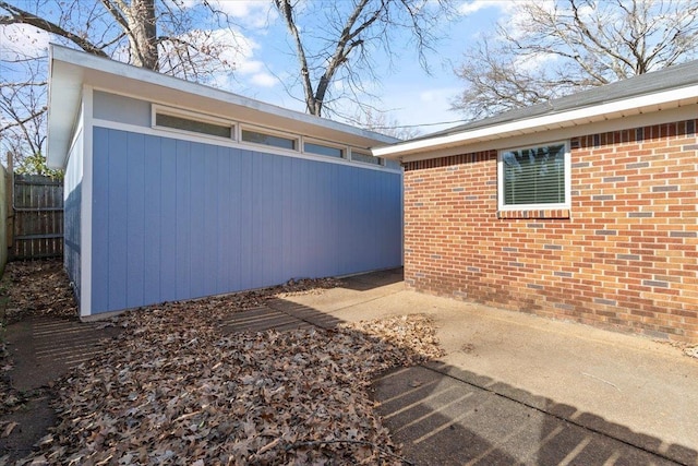 view of side of home featuring brick siding and fence