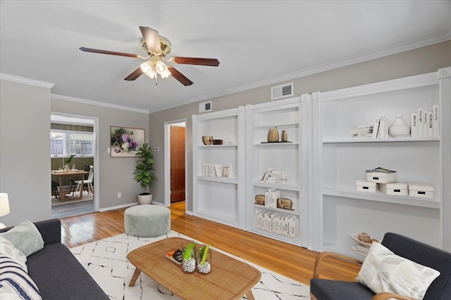 living area with light wood-style floors, visible vents, ornamental molding, and a ceiling fan