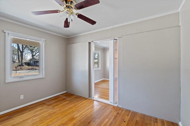 unfurnished bedroom featuring baseboards, light wood finished floors, a ceiling fan, and crown molding