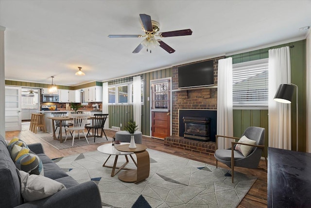 living room featuring a brick fireplace, ceiling fan, and light wood finished floors