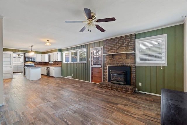 unfurnished living room featuring visible vents, dark wood finished floors, a fireplace, and ceiling fan