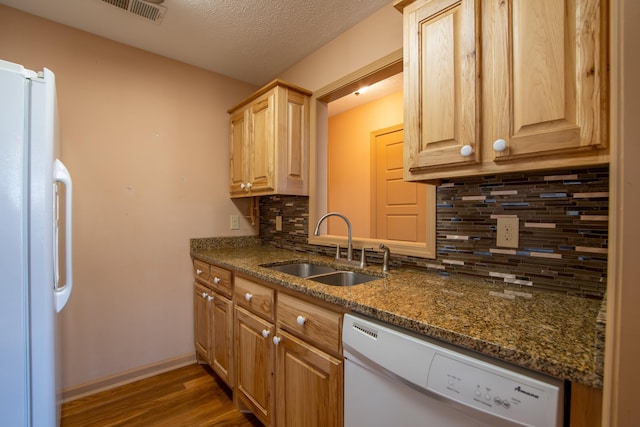 kitchen with sink, a textured ceiling, dark hardwood / wood-style flooring, white appliances, and dark stone counters