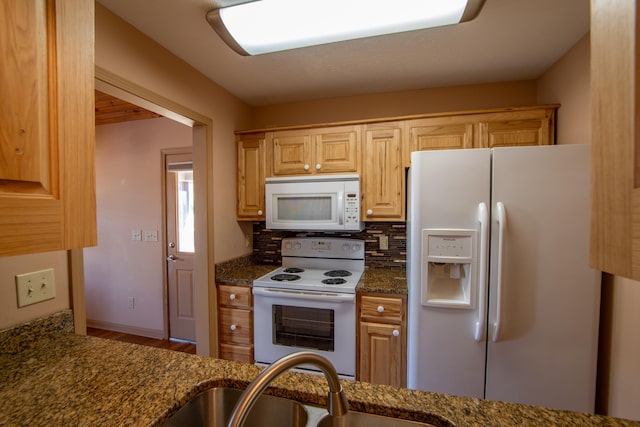 kitchen with light brown cabinetry, sink, backsplash, dark stone counters, and white appliances