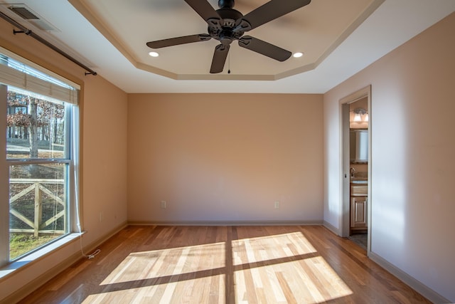 unfurnished room with hardwood / wood-style floors and a tray ceiling