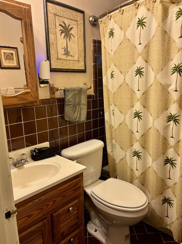 bathroom with curtained shower, tile walls, tile patterned flooring, vanity, and toilet