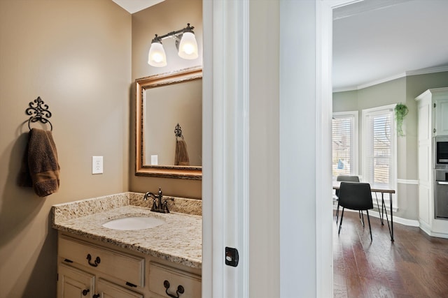 bathroom with ornamental molding, vanity, and wood-type flooring