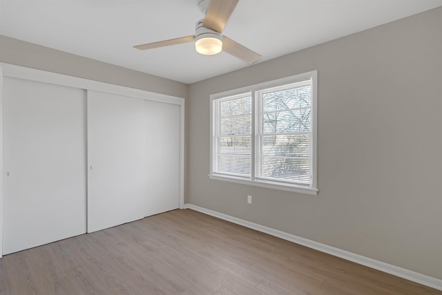 unfurnished bedroom featuring ceiling fan, light wood-type flooring, and a closet