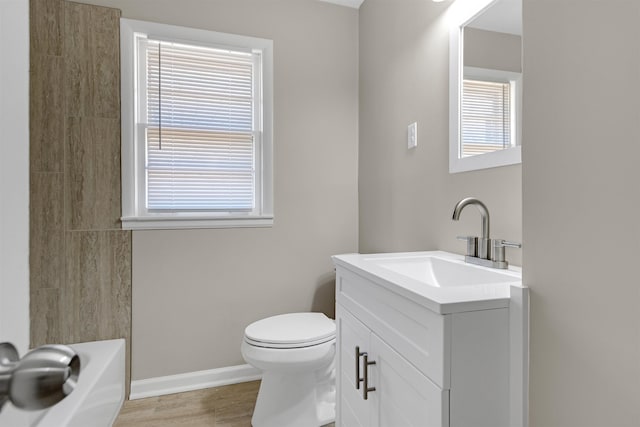 bathroom with hardwood / wood-style flooring, vanity, toilet, and plenty of natural light