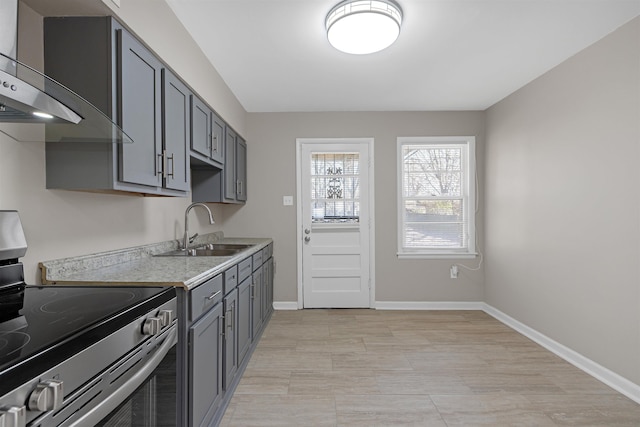 kitchen with gray cabinetry, sink, stainless steel electric stove, and wall chimney range hood