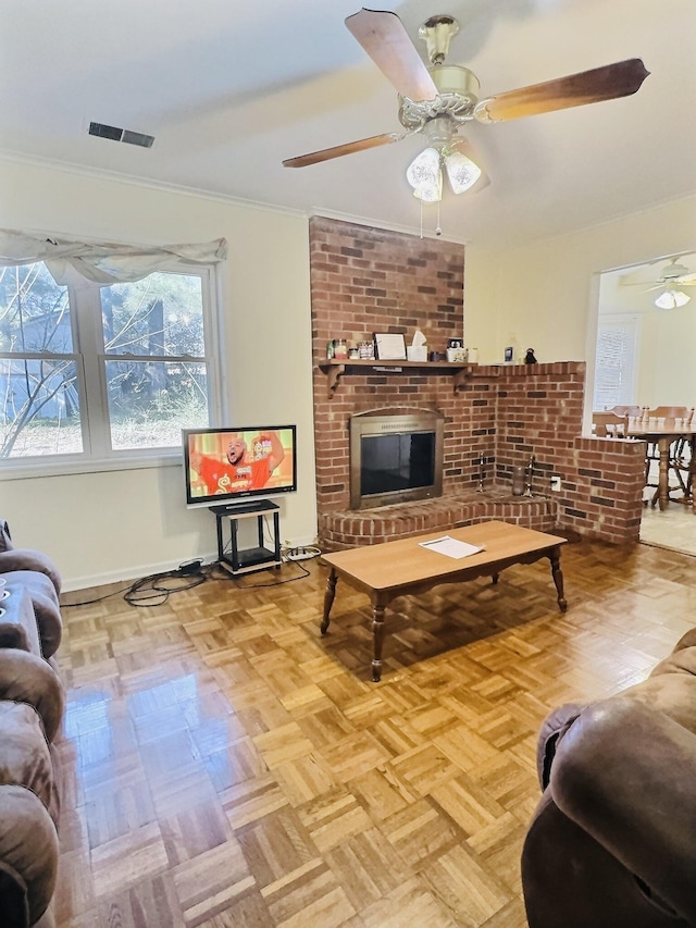 living room featuring a brick fireplace, light parquet flooring, ornamental molding, and ceiling fan