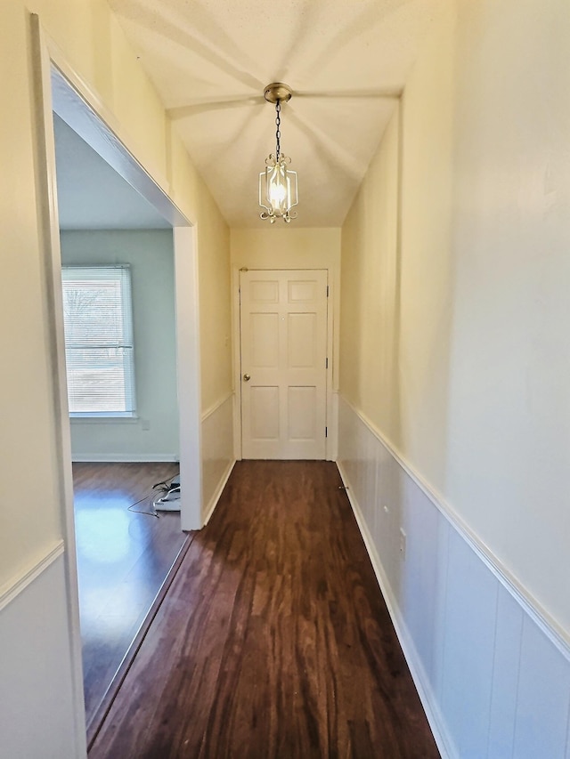 corridor with an inviting chandelier and dark hardwood / wood-style floors