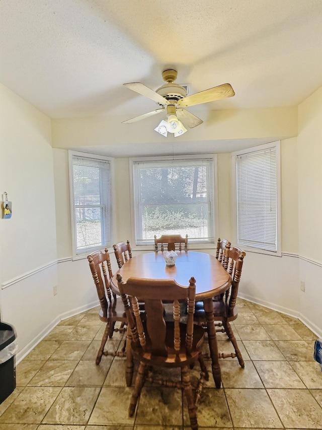 tiled dining space with ceiling fan and a textured ceiling