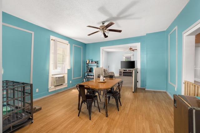 dining area with cooling unit, ceiling fan, a textured ceiling, and light wood-type flooring