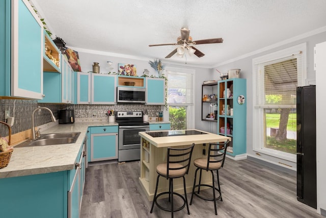 kitchen with a breakfast bar, blue cabinets, wood-type flooring, sink, and stainless steel appliances