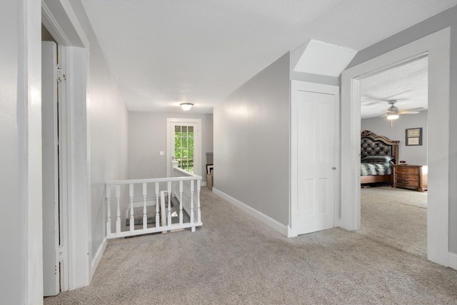 hallway featuring light colored carpet and a textured ceiling