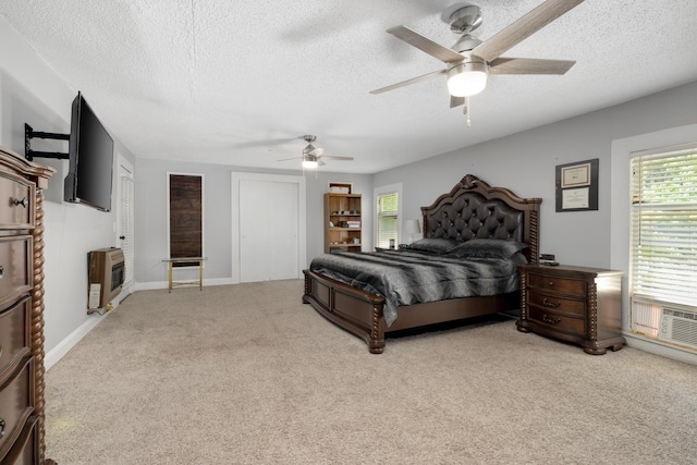 bedroom featuring ceiling fan, carpet, heating unit, a textured ceiling, and a closet