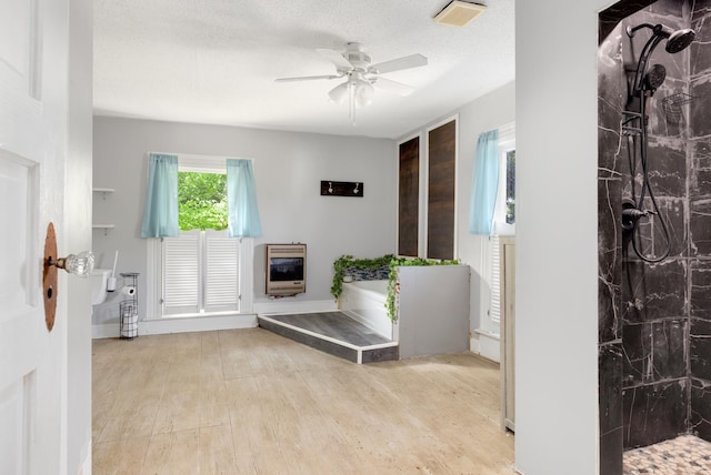 foyer entrance featuring ceiling fan, light hardwood / wood-style floors, heating unit, and a textured ceiling