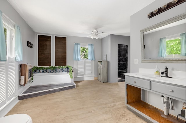 bathroom featuring heating unit, wood-type flooring, a bathtub, vanity, and ceiling fan