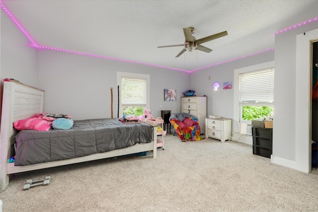 carpeted bedroom featuring ceiling fan and a textured ceiling