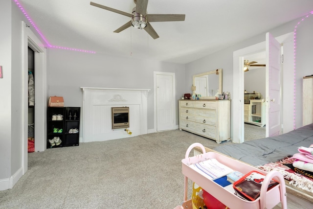 bedroom featuring ceiling fan, light colored carpet, a fireplace, and heating unit