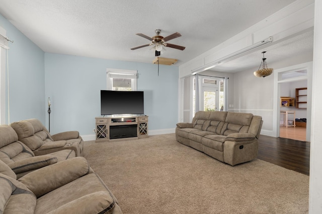 living room with ceiling fan, carpet floors, and a textured ceiling