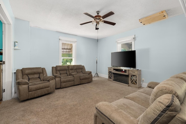 living room with ceiling fan, light carpet, and a textured ceiling