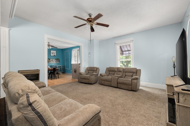 living room with light carpet, ceiling fan, and a textured ceiling