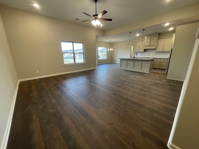 kitchen with a ceiling fan, open floor plan, baseboards, and dark wood-style flooring