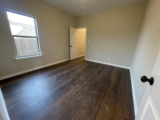 unfurnished room with dark wood-style flooring and baseboards