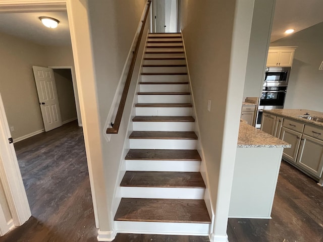 staircase with baseboards, wood finished floors, and recessed lighting