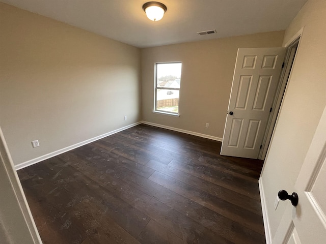 empty room with visible vents, baseboards, and dark wood-style flooring