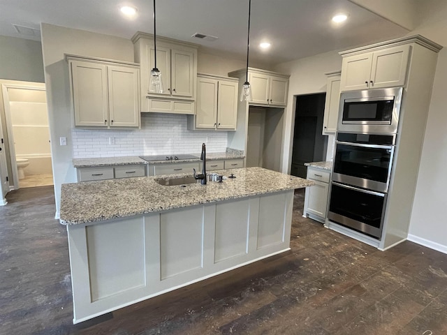 kitchen with visible vents, light stone counters, appliances with stainless steel finishes, a sink, and backsplash