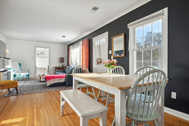 dining space with crown molding and light hardwood / wood-style flooring