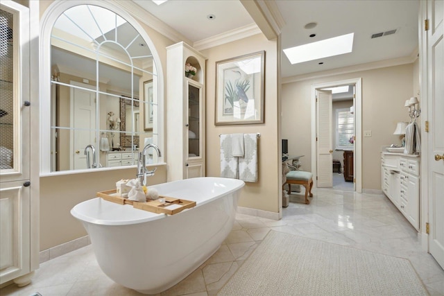 bathroom with a washtub, vanity, a skylight, and ornamental molding