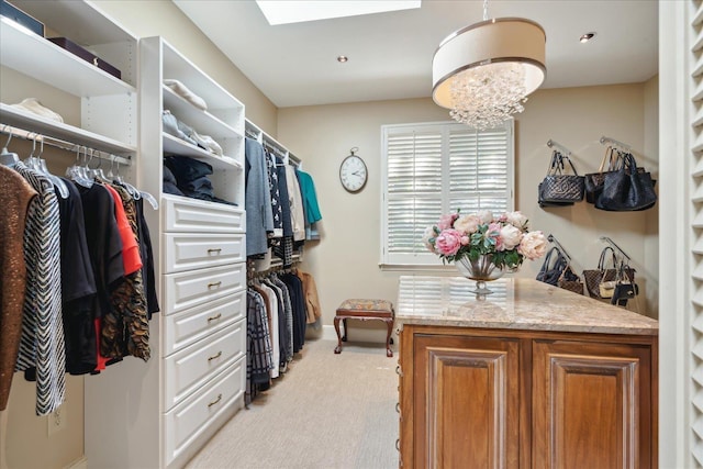 spacious closet with light carpet, an inviting chandelier, and a skylight