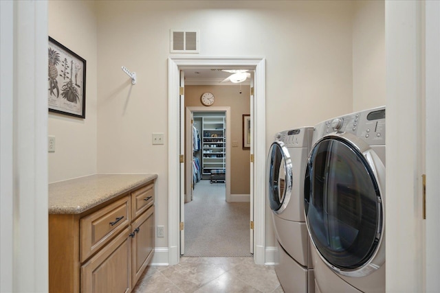 laundry room with light tile patterned floors, washer and clothes dryer, and cabinets