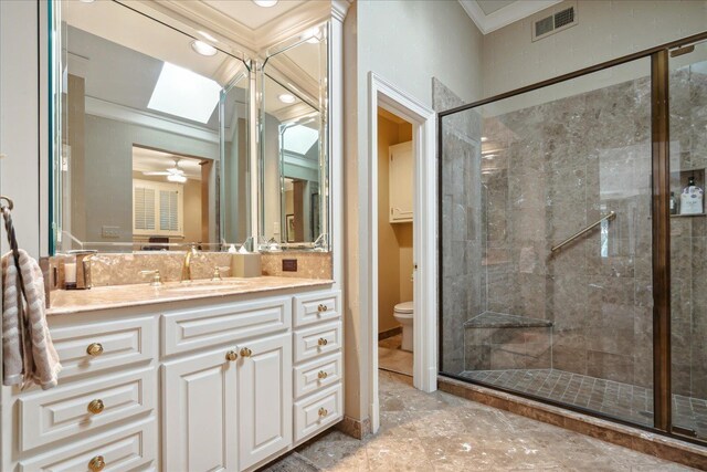 bathroom with a shower with shower door, vanity, ceiling fan, toilet, and crown molding