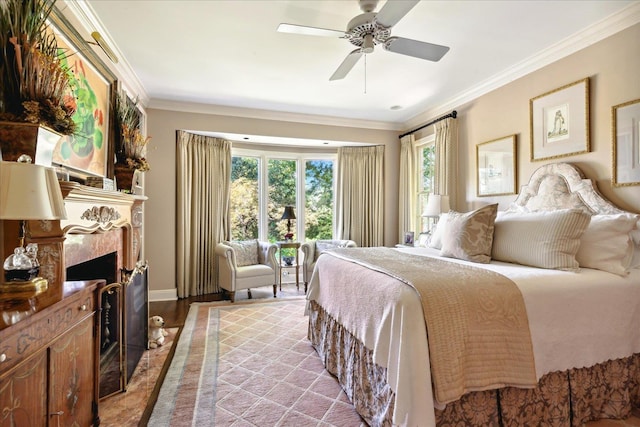 bedroom with crown molding, ceiling fan, a fireplace, and light wood-type flooring