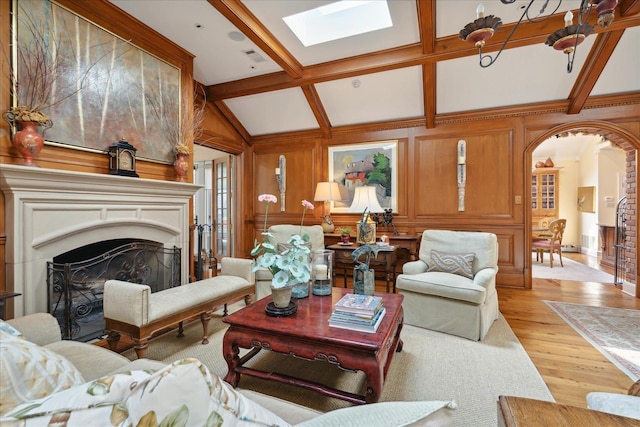 living room with lofted ceiling with skylight, wooden walls, and light wood-type flooring