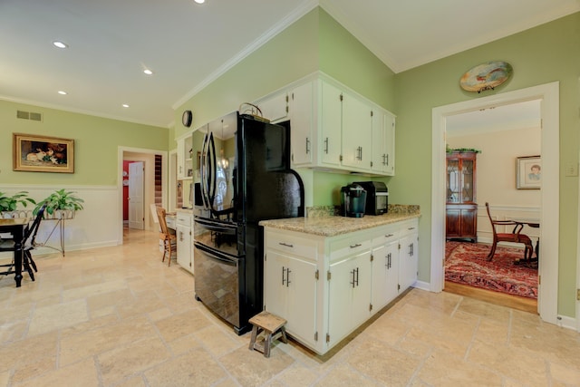 kitchen featuring ornamental molding, black fridge, white cabinets, and light stone counters