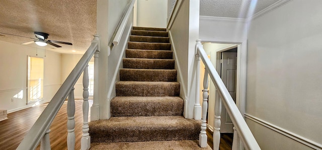 staircase with crown molding, ceiling fan, wood-type flooring, and a textured ceiling