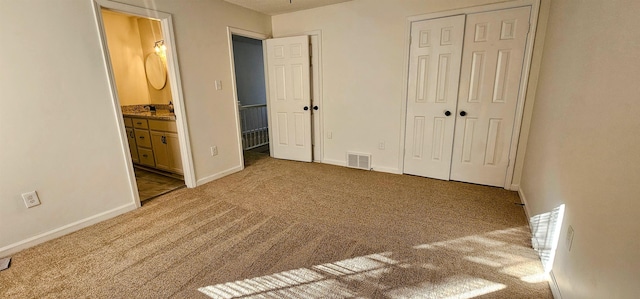 unfurnished bedroom featuring ensuite bathroom, carpet flooring, and a closet