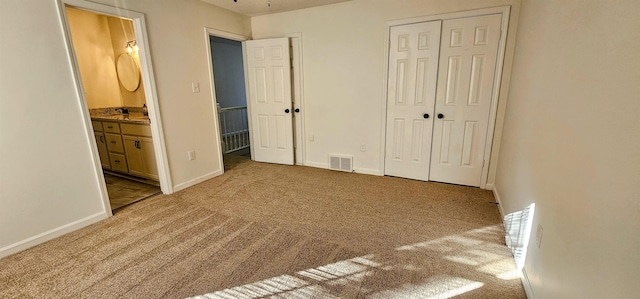 unfurnished bedroom featuring carpet flooring, ensuite bath, and a closet