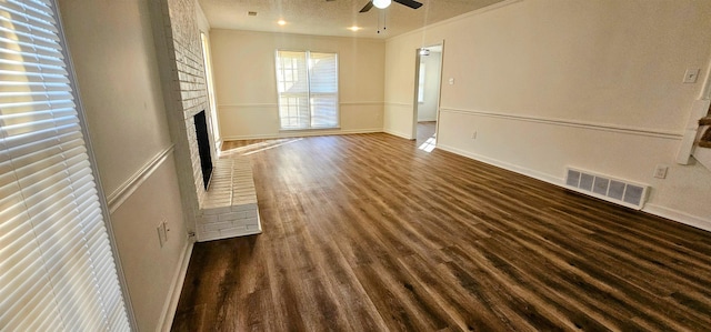 unfurnished living room with ceiling fan, a brick fireplace, a textured ceiling, and dark hardwood / wood-style flooring