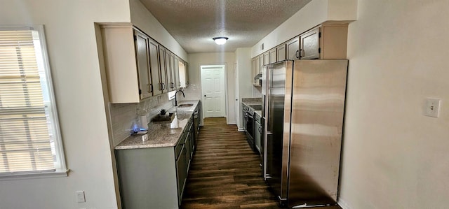 kitchen with sink, a textured ceiling, dark hardwood / wood-style floors, stainless steel fridge, and backsplash