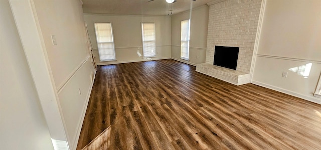 unfurnished living room with a fireplace, dark hardwood / wood-style floors, and ceiling fan